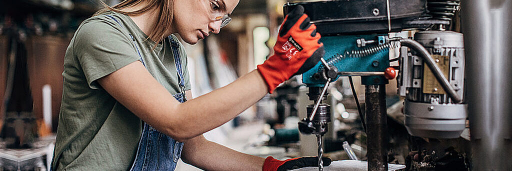 An engineer wearing protective gloves is focused on operating a machine, ensuring workplace safety